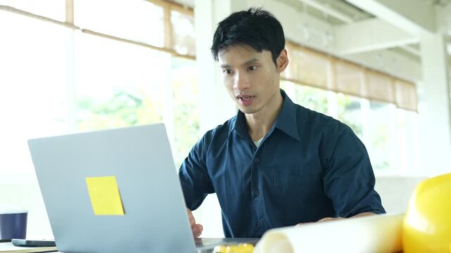Architect working on house construction plans with blueprints, color samples, measuring tools and architectural drawings on a wooden desk.