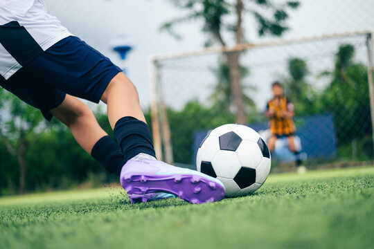 Kid boy leg kicking soccer ball on green grass field action. conceptual metaphor for youth sports training team competition fitness health wellness and active lifestyle