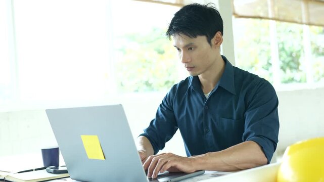 Architect working on house construction plans with blueprints, color samples, measuring tools and architectural drawings on a wooden desk.