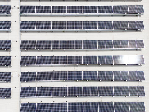 Solar panels mounted in uniform rows on building facade, innovative photovoltaic installation and renewable energy concept.