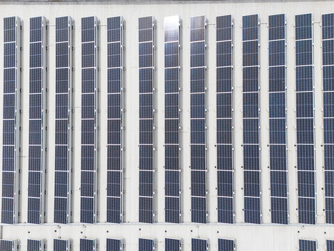 Solar panels mounted in uniform rows on building facade, innovative photovoltaic installation and renewable energy concept.