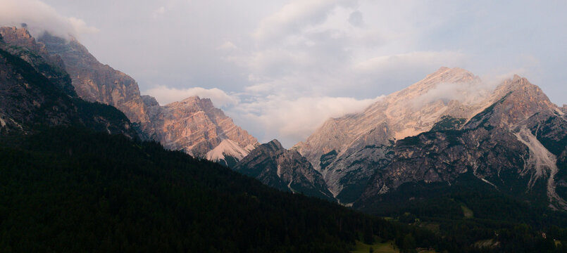 Aerial vertical shot of a mountain ridge featuring sharp rock formations, lush green meadows, and expansive scenic vistas 