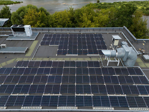 aerial view of solar panel array mounted in rows on flat commercial rooftop, renewable energy and photovoltaic installation detail concept.