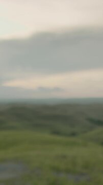 Young woman stands on a hill in indonesia, watching the sunset over lush green hills, painting the sky with orange and pink hues