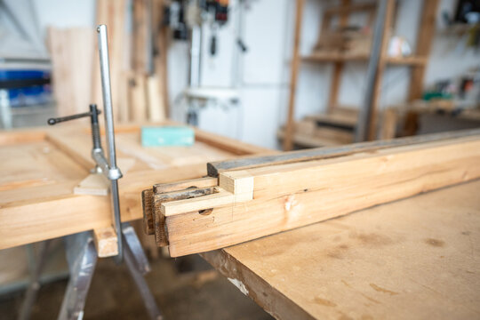 Old and new parts of window frame and wooden patch for reconstruction at worktable, workbench in woodworking shop with lumber material, preparation for professional restoration of antique furniture.