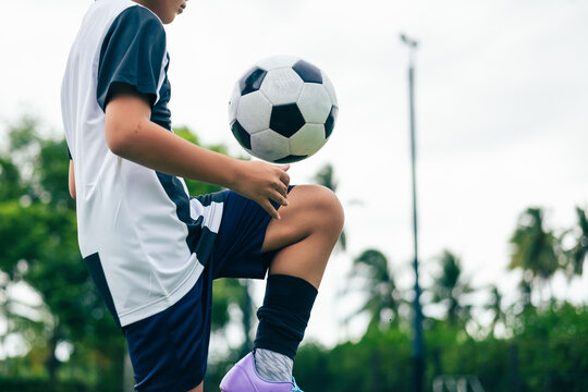 Kid boy leg kicking soccer ball on green grass field action. conceptual metaphor for youth sports training team competition fitness health wellness and active lifestyle