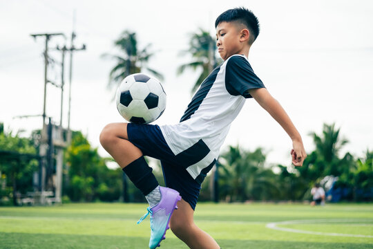 Kid boy leg kicking soccer ball on green grass field action. conceptual metaphor for youth sports training team competition fitness health wellness and active lifestyle