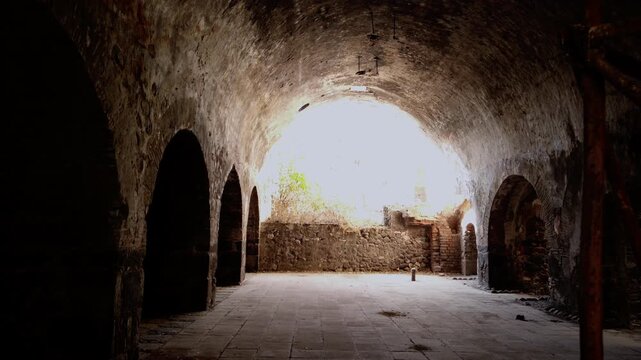 Interior view of the historic Hacienda Coahuixtla featuring large stone arches, vaulted ceilings and sunlight streaming through the open courtyard entrance in Morelos, Mexico