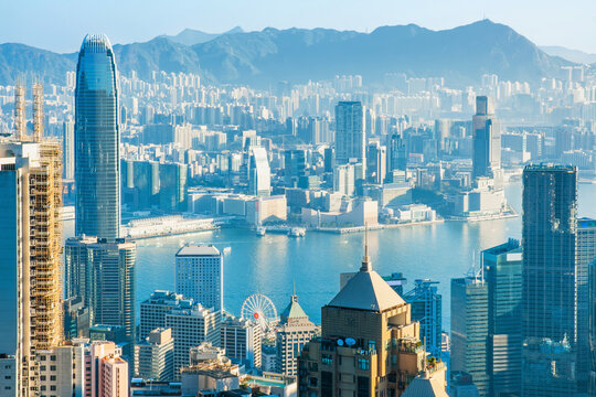Aerial cityscape overlooking Victoria Harbour in Hong Kong city, China. Skyscrapers, waterfront districts and surrounding mountains. Urban planning, modern architecture, economic growth