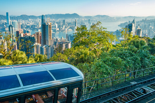 Mountain funicular overlooking Hong Kong city skyline and Victoria Harbour, China. Urban transport, sustainable mobility, tourism, city infrastructure, nature and megacity, public transportation