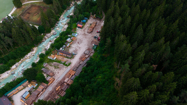 aerial view of a village with river and buildings in neutral calm setting from above with concrete, wood, and metal materials and green, brown, blue, and red colors.