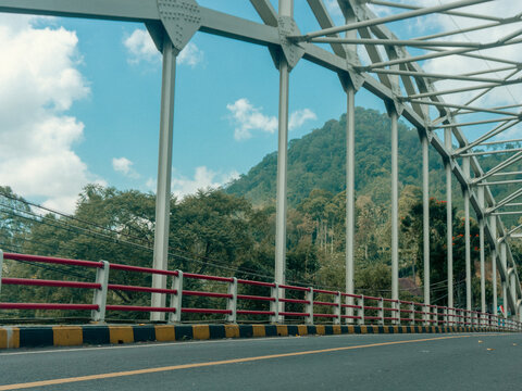 The arch-style bridge frames the small Javanese-style roof peaks in the south, making them the focal point.