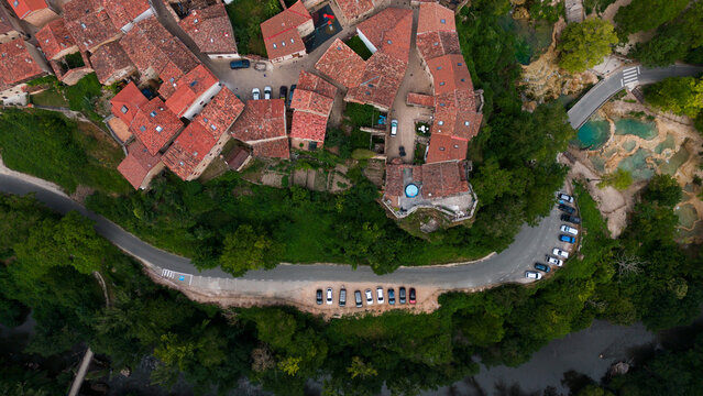 peaceful aerial view of a village with red-tiled roofs and green surroundings in a serene setting, showcasing real estate and architecture, Risco los camellos, Cascada de Orbaneja del Castillo