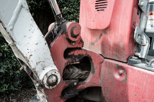 Detailed view of  the hydraulic arm and pivot of a small mechanical digger and excavator seen on a housing development site. The drivers cockpit is on the far right.