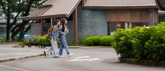 Obraz premium Asian women tourists with backpacks walking on street during vacation trip