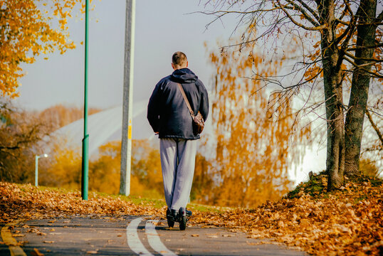 The guy rides an electric scooter in the autumn Park
