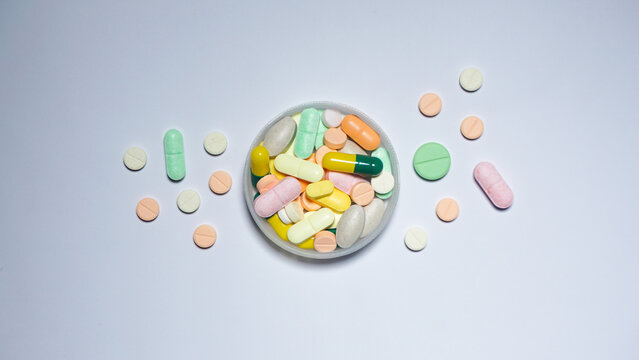 pills and capsules on bottle cap. Colorful medicines on bottle cap on top of white surface. 