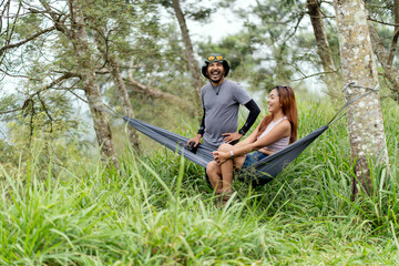 Obraz premium Asian couple relaxing together in a hammock surrounded by lush tropical nature