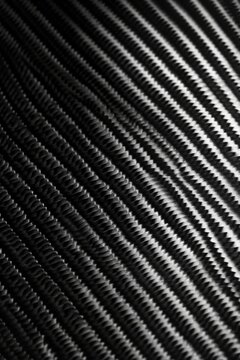 Close-up of a diagonal carbon fiber texture with light reflections