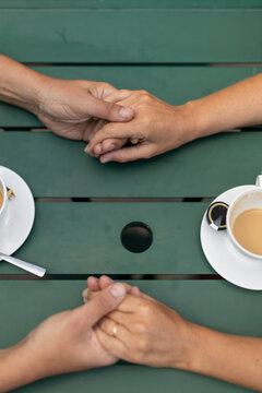 Overhead view of a couple holding hands at a cafe table
