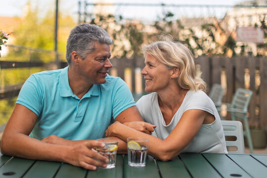 Smiling mature couple making eye contact at an outdoor table