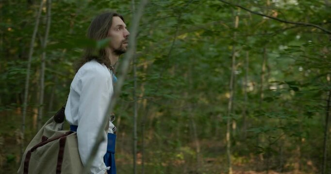 Caucasian man with long hair and Ukrainian traditional folk attire walk wandering on nature. 4K 10-bit