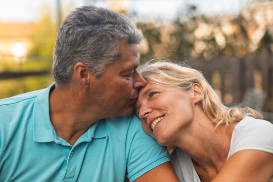Tender forehead kiss between a mature couple outdoors