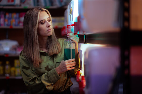 Conscious Woman Refilling Reusable Glass Bottle At Detergent Dispenser Station     
 Eco friendly young lady consumer filling container with liquid soap in retail store 