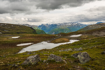 Glacial meltwater ponds reflecting cloudy skies on the rocky tundra of Aurlandsfjellet mountain pass along the scenic route between Aurland and Lærdal, Norway. © Michele