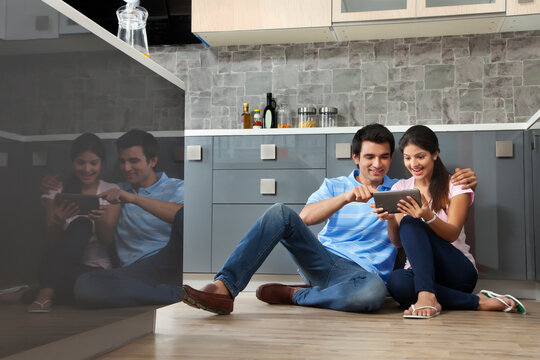 Full length of couple using digital tablet together in kitchen