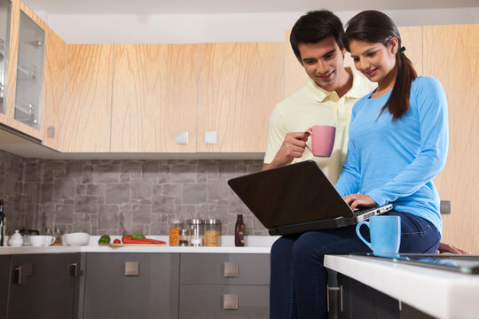 Young couple using laptop in kitchen