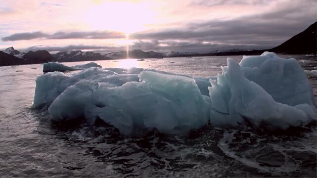 Majestic icebergs gently float across the shimmering waters of the Arctic Ocean. Sunlight dances on the surface near Svalbard, Norway, during the magical summertime.