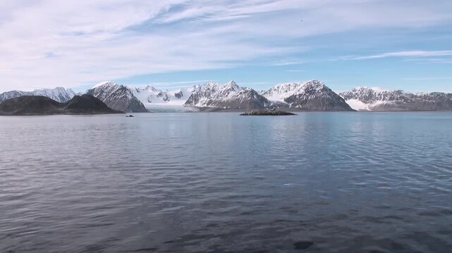 Witness the sublime beauty of Svalbard, Norway, during its bright summertime. Snow-capped mountains stand tall above tranquil Arctic waters, dotted with small, rugged islands.