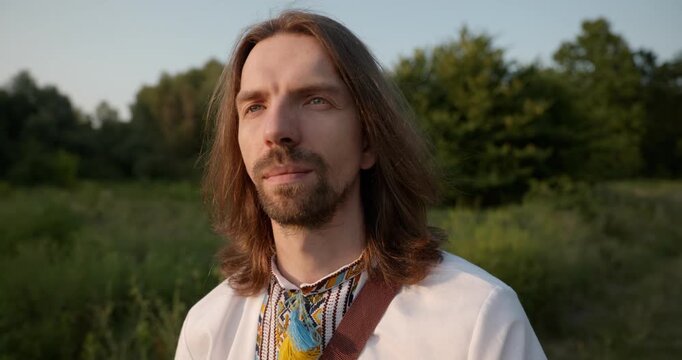 Caucasian man with long hair and Ukrainian traditional folk attire walk wandering on nature. 4K 10-bit