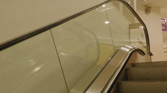Modern escalator with glass balustrade inside a commercial building or shopping mall.