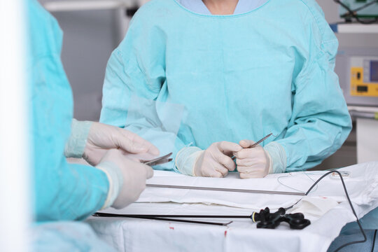 Nurse holds bandage in her hands. Preparation of instruments for laparoscopic surgery. Hands in protective gloves. Modern surgery