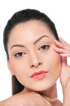 Pretty young woman touching her face over white background 