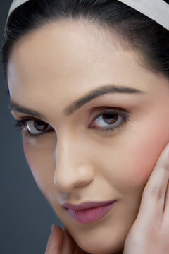 Portrait of an attractive female touching her face over colored background 