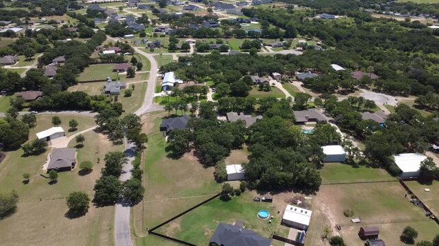 Single family home sites nestle among dense oak groves near County Road 602 in Dallas Fort Worth. High perspective displays fenced perimeters, custom rooflines, circular drives. Burleson, TX