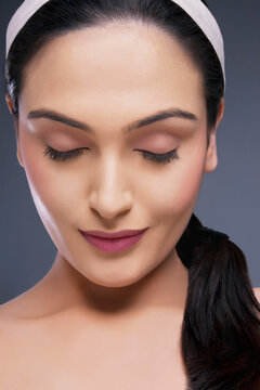 Head shot of beautiful calm female with eyes closed over colored background 
