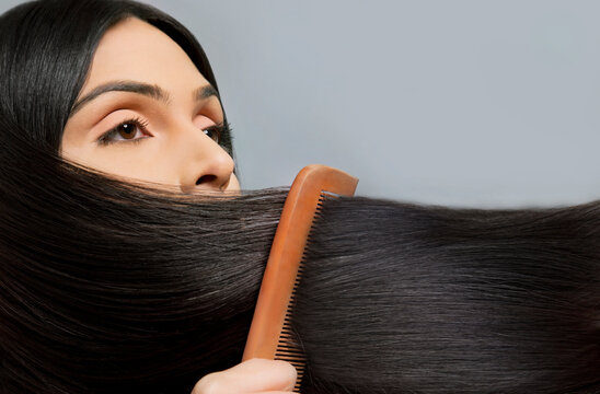 Close-up of woman combing her beautiful long hair over colored background 