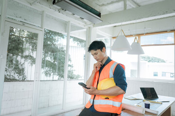 Fototapeta premium Construction worker in a safety vest holding a hard hat and looking stressed at a building site, representing workplace pressure, construction challenges and project management.
