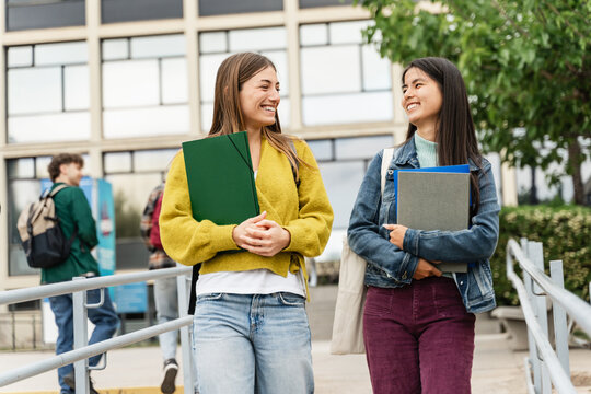 Young diverse student women walking around business university building