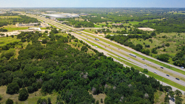 Multilane freeway lanes stretch past heavy green foliage along South Burleson Boulevard near Fort Worth. Semi trucks, commuter traffic traverse central transport corridors, Burleson, TX