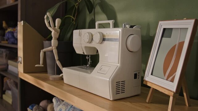 Sewing machine sitting on wooden shelf next to artist mannequin, camera panning slowly. Footage is perfect for fashion design school promotions, tailoring business ads, or DIY craft tutorials