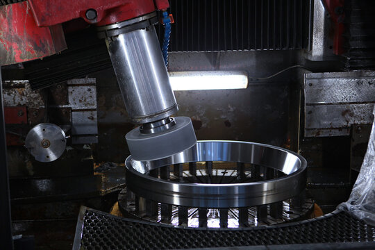 Manufacturing process of bearing. Industrial equipment. Metalworking machine. Сlose-up of grinding or machining process of metal bearing on an industrial machine with coolant supply. Industrial photog