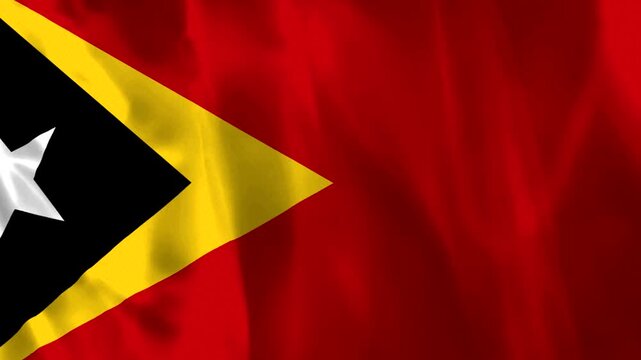 Waving flag of East Timor featuring a red field with yellow and black triangles and a white star