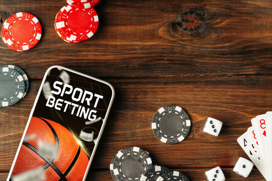 Engaging with sport betting using a mobile phone on a wooden table with chips and dice