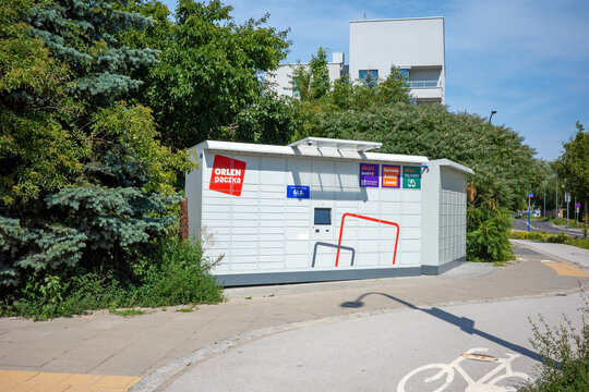 Warsaw, Poland - July 26 2026: Modern outdoor automated parcel locker station located on a sunny urban street surrounded by green trees.