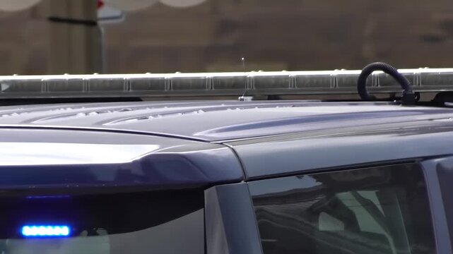 Close-up of flashing red and blue emergency light bar on roof of a parked police vehicle.